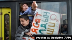 Women gesture from a police van after they were arrested while protesting against gender-based violence to mark International Women's Day in Bishkek on March 8, 2020.