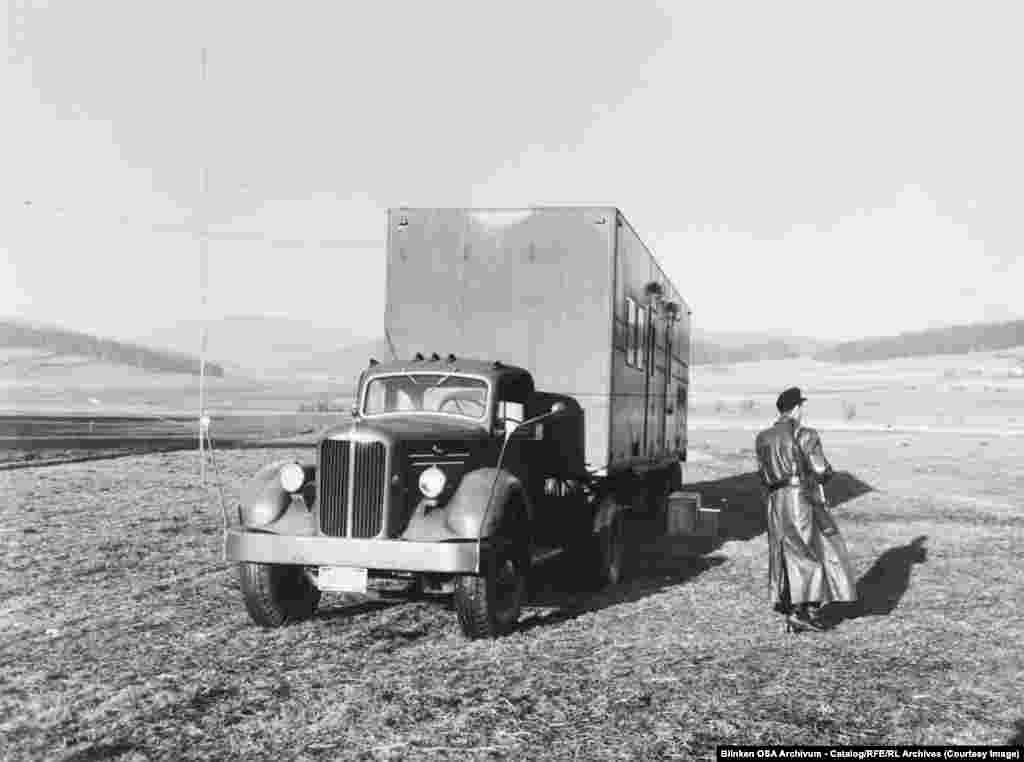 Silahlı mühafizəçi Qərbi Almaniyada, Çexoslovakiya ilə sərhəd yaxınlığında orta-dalğa radioötürücü maşını qoruyur. 1955-ci il.Kommunist ölkələri Azad Avropa Radiosu və AzadlıqRadiosunun yayımlarını vurmağa başlayanda Azad Avropa Radiosu onlarla mobil ötürücü stansiyalar quraşdırdı. Bu fotodakı da onlardan biri idi. Bu stansiyalar "Dəmir pərdə"nin yaxınlığında işləyə bilirdilər.
