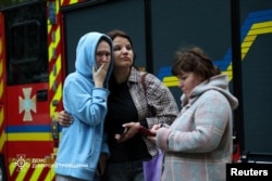 Residents react as they stand near a residential building damaged during a Russian missile strike on the Ukrainian city of Dnipro on September 20.