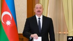 Азербайджанский лидер Ильхам Алиев опускает бюллетень в урну на избирательном участке в городе Ханкенди, 7 февраля 2024 года