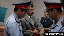 Полиция қызметкерлері сот залында Евгений Жовтистің қолына кісен салып жатыр. Алматы облысы, Бақанас, 3 қыркүйек 2009 жыл.