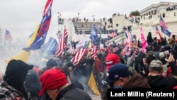 Приврзаниците на американскиот претседател Доналд Трамп реагираат на солзавец за време на судир со полицијата пред зградата на Капитол во САД.