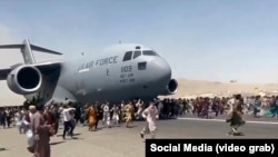 Afghans try to block a U.S. Air Force plane at Hamid Karzai International Airport as it prepares to take off on August 16.