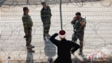 Сирийский друз разговаривает с израильскими солдатами через решетку и колючую проволоку на линии размежевания на Голанских высотах. Мадждаль-Шамс, 17 июля 2025 года