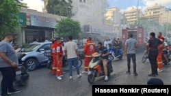 Жители на Сайда в Южен Ливан и спасителни екипи са се събрали край сграда, от която излиза дим след взрив на устройства, използвани от членове на Хизбула, 18 септември 2024 г.