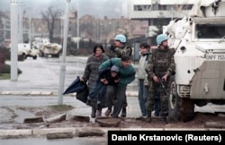 Stanovnici Sarajeva skrivaju se od snajperske vatre iza oklopnog vozila UNPROFOR-a u centru Sarajeva, 1993.