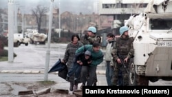 غیر نظامیان ساکن سارایوو پشت یک خودروی زرهی سازمان ملل متحد پناه گرفته‌اند