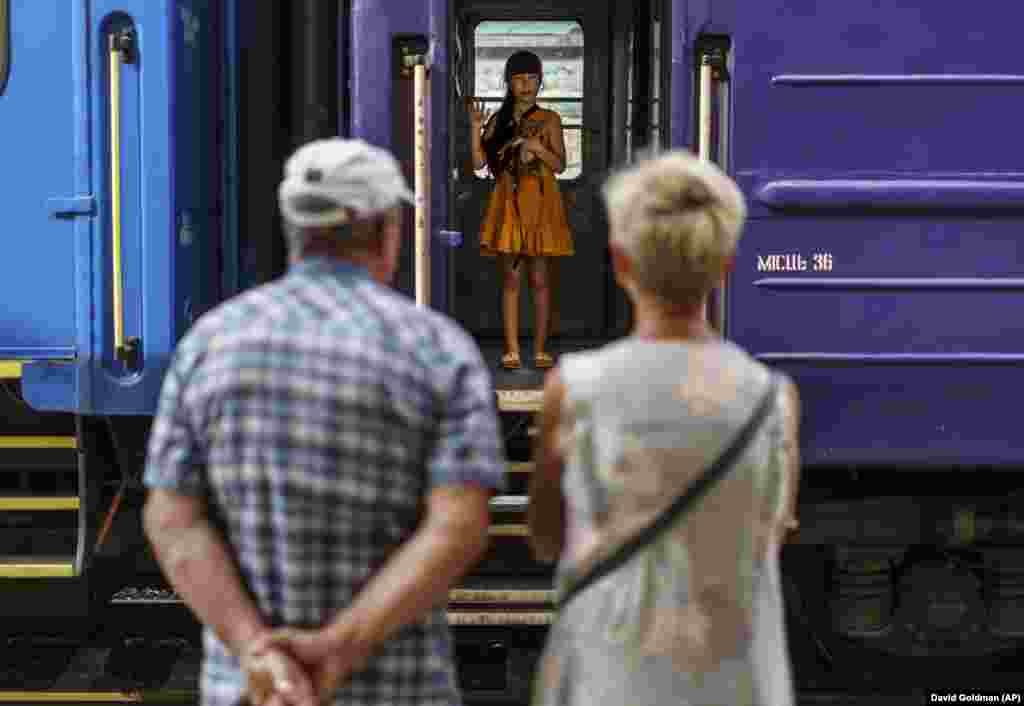 A young girl holding her dog waves goodbye to her grandparents from an evacuation train departing Pokrovsk, in the Donetsk region, on August 2, 2022. The Ukrainian government issued an order to residents to leave the Donetsk region out of concern that there might not be access to heating, electricity, or even clean water for its residents.