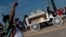 A man raises his fist as mourners watch the casket of George Floyd carried by a white horse-drawn carriage to his final resting place at the Houston Memorial Gardens cemetery in Pearland, Texas on June 9, 2020.