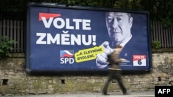 Un pieton trece pe lângă un panou electoral al unui partid de extremă dreapta care îndeamnă cehii să „voteze pentru schimbare”. 