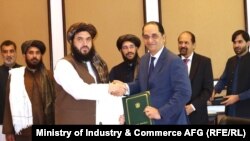 د پاکستان د سوداګرۍ مرستیال وزیر جاوېد پاول (ښي لوري ته) او د طالبانو د صنعت او سوداګرۍ وزارت مرستیال احمد الله زاهد په اسلام اباد کې د هوکړې تر لاسلیک وروسته روغبړ کوي - د جولای ۲۳مې انځور 