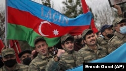 Azerbaijani soldiers with a national flag celebrate the transfer of the Lachin region to Azerbaijan's control on December 1.