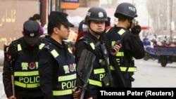 Қашғардағы көшелердің бірінде тұрған қарулы полиция қызметкерлері. Қытай, Шыңжай-Ұйғыр автономиялық өлкесі, 2017 жыл.