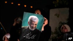 Un susținător al lui Saeed Jalili, candidat la alegerile prezidențiale din 28 iunie, ține afișul său în timpul unei adunări de campanie în Teheran, Iran, miercuri, 26 iunie 2024.