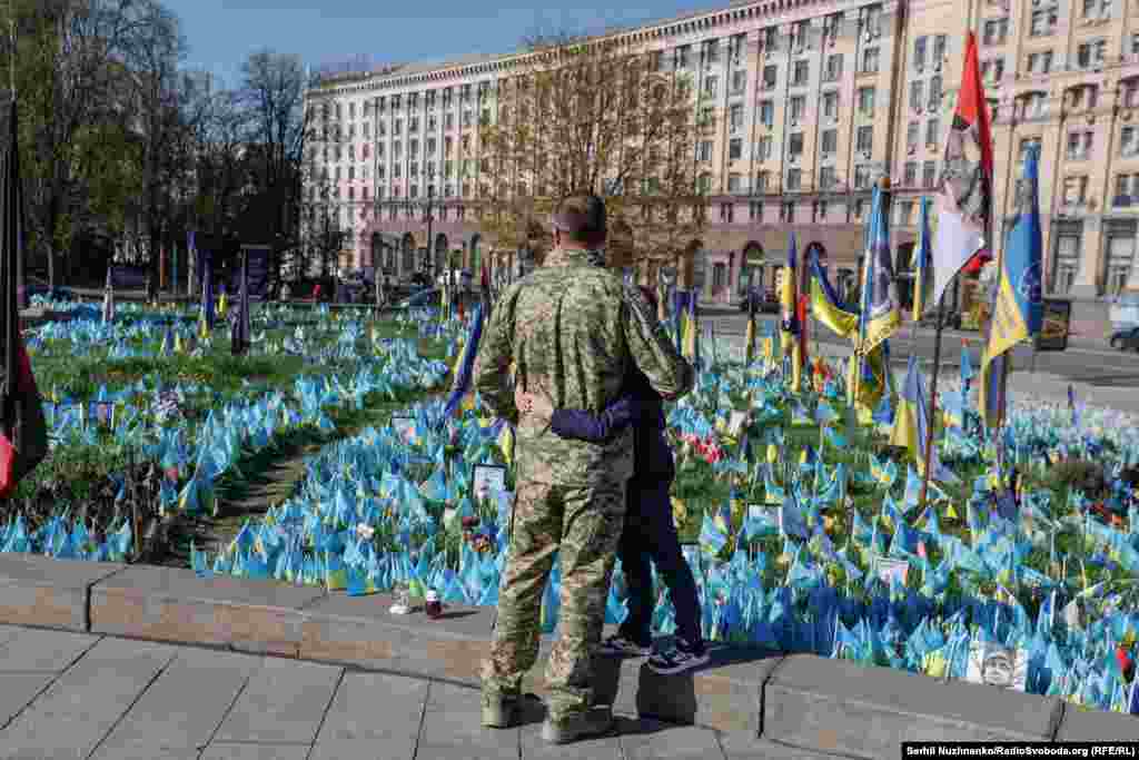 Вайсковец абдымае сына каля народнага мэмарыяла зь сьцяжкамі на майдане Незалежнасьці ў Кіеве. Красавік 2025 году