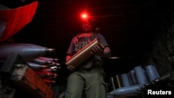 Військовослужбовець 141-ї ОМБр ЗСУ несе боєприпаси для самохідної гаубиці 2С1 «Гвоздика» на позиції в Донецькій області, 3 вересня 2025 року