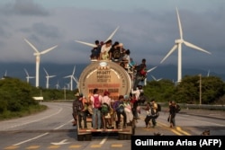 Вантажівка перевозить мігрантів на каравані, що прямує до США, проїжджаючи повз вітрову електростанцію на шляху із Сантьяго-Нільтепеку до Хучітану. Мексика
