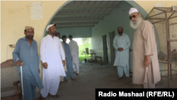 Mian Abdul Haq, widely known as Mian Mitha (right), strolls around his residence among his followers.