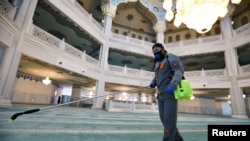 A specialist wearing a protective mask sprays disinfectant as he sanitizes the Moscow Cathedral Mosque to prevent the spread of coronavirus in Moscow on March 27.