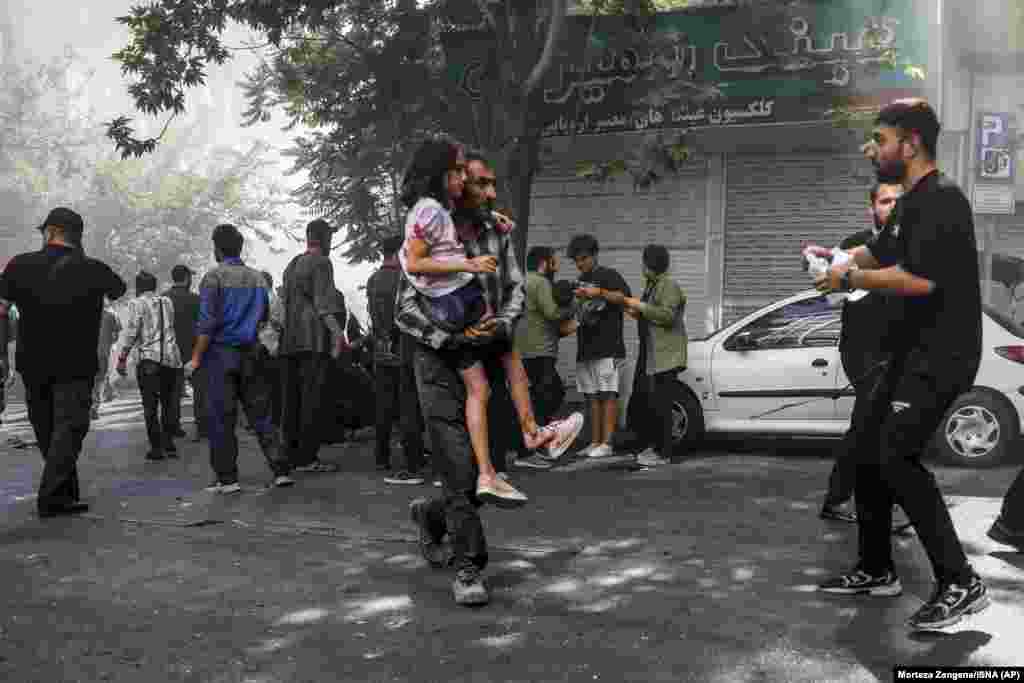 Мужчына нясе параненую дзяўчынку пасьля выбуху ў цэнтры Тэгерану 15 чэрвеня 2025 падчас ізраільскіх удараў па цэлях ува ўсім Іране.