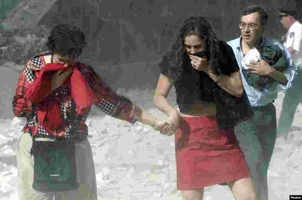 New York-ul este cuprins de haos. Zeci de oameni răniți aleargă șocați pe străzi și mulți alții sunt captivi în World Trade Center. Unii dintre aceștia au sărit în gol de la peste o sută de metri înălțime din clădirile cuprinse de fum și flăcări. În imagine, supraviețuitori ies din World Trade Center după ce clădirile au fost atacate. &nbsp;