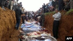 A picture released on April 6 by the opposition Local Coordination Committees in Syria (LCC) purportedly shows people standing around a mass grave in the town of Taftnaz.
