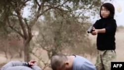 Скриншот видео, на котором мальчик осуществляет казнь двух мужчин, которых ИГ назвало российскими агентами.