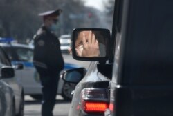 Almatynyň köçesinde duran maşynyň içindäki ýüzi goragly adam.