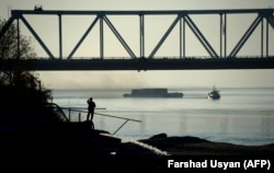 An Afghan man watches a ship travel along the Amu-Darya River on the border between Afghanistan and Uzbekistan