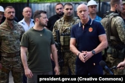 На передньому плані: президент України Володимир Зеленський (ліворуч) і мер Одеси Геннадій Труханов навпроти житлової багатоповерхівки, пошкодженої російською ракетою. Одеса, 18 червня 2022 року