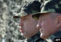 Олександр Турчинов, виконуючий обов'язки президента України (зліва), та міністр оборони України Ігор Тенюх (справа) беруть участь у військових навчаннях поблизу Києва, 14 березня 2014 року