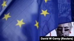 Снимката е илюстративна. Плакат с образа на руския президент Владимир Путин се вижда зад знамето на ЕС по време на митинг на членове на украинската общност в Чешката република, които се противопоставят на руската намеса в Крим. Прага, март 2014 г.