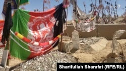 The Afghan flag and the Taliban banner top the graves of Faizullah's three brothers. Two of them were killed while working for the Afghan police while the other was a Taliban fighter. (video grab)