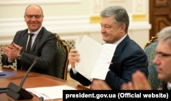 Президент України Петро Порошенко під час підписання закону «Про забезпечення функціонування української мови як державної». Ліворуч від нього – спікер парламенту Андрій Парубій. Києві, 15 травня 2019 року