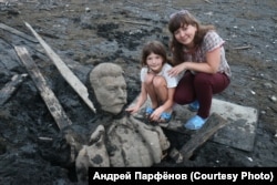 The wife and daughter of photographer Andrei Parfyonov pose with fragments of the Stalin statue.