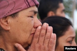 A woman prays as a motorcade carrying the body of President Islam Karimov passes by in Tashkent on September 3.