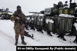 Укарінскі вайсковец каля разьбітай пад Харкавам у пачатку сакавіка 2022 году калёны вайсковай тэхнікі 200-й мотастралковай брыгады.