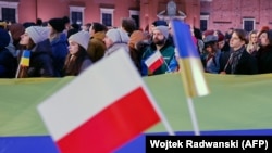 Люди з польськими та українськими прапорами слухають промову президента України Володимира Зеленського та президента Польщі Анджея Дуди у дворі Королівського замку у Варшаві, Польща, 5 квітня 2023