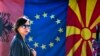Žena prolazi pored zastava Albanije, EU i Severne Makedonije na pijaci u Skoplju, 3. februara 2020.