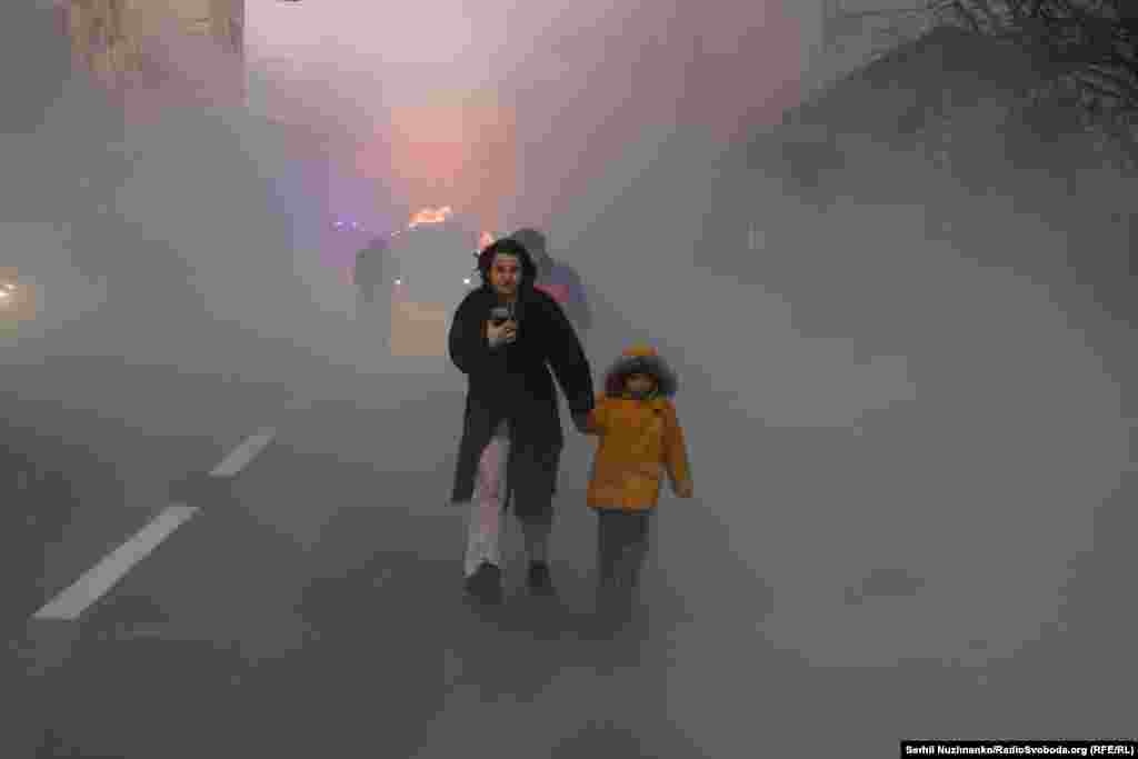 O femeie duce un copil departe de mașina în flăcări din spatele lor.&nbsp;