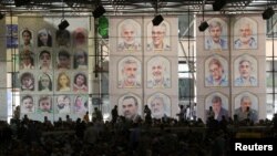 عکسی که خبرگزاری رویترز از نمازجمعه ۳۰ خرداد تهران منتشر کرد و تصویر استاندار یزد (ردیف پایین، عکس دوم از راست) روی بنر نصب شده بود