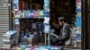 (FILES) An Afghan vendor reading a book waits for customers at his roadside bookshop in Kabul on November 3, 2024.