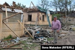 Житель Новопавлівки Микола Макарович біля сусідського розбитого російськими атаками будинку, травень 2025 року