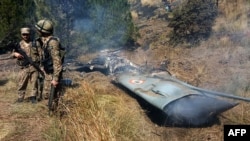 Pakistani soldiers stand next to what Pakistan says is the wreckage of an Indian fighter jet shot down in Pakistan-controlled Kashmir in the Somani area of Bhimbar district near the Line of Control on February 27.