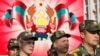 Войници от самообявилата се Приднестровска молдовска република (ПМР) по време военен парад в Тираспол през 2012 г. Зад тях е гербът на ПМР.
