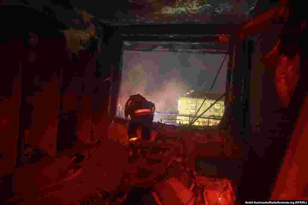 Рятувальник у пошкодженій атакою квартирі біля вікна, що залишилося без шибок. Із нього видно дим, що здіймається на місці атаки.Пошкодження та падіння уламків зафіксували також у Голосіївському, Деснянському та Подільському районах міста