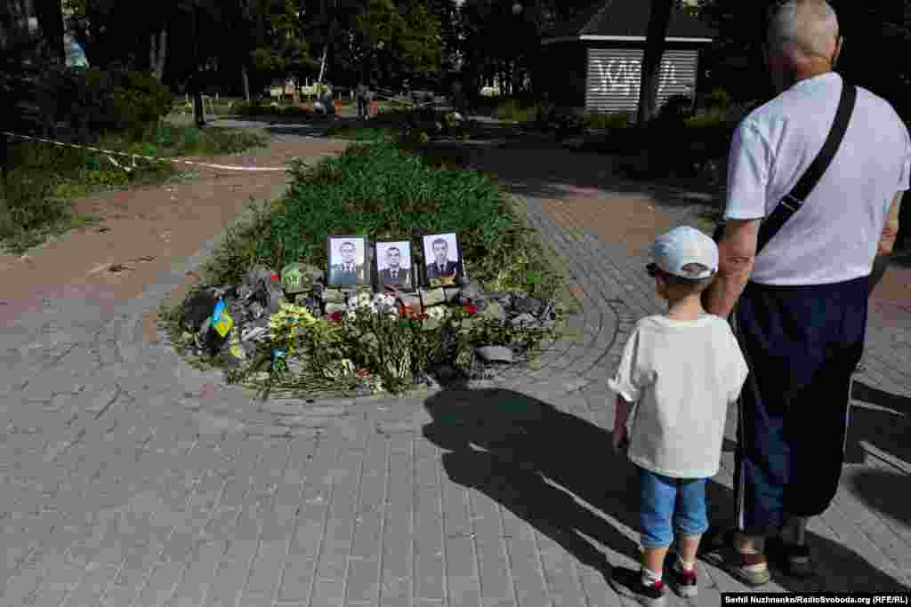 Чоловік із дитиною біля символічного меморіалу неподалік від метро «Шулявська» в Києві, де під час російської атаки загинули 3 рятувальники. Київ, 6 червня 2025 року