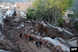 Спасатели на улице, разрушенной наводнением в селении Летура к юго-западу от Валенсии. 30 октября 2024 года