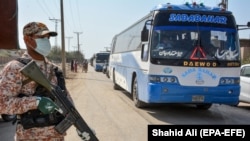 A soldier stands guard as buses carry pilgrims returning from Iran via the Pakistan-Iran border town of Taftan in March.