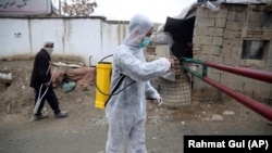A volunteer in a protective suit sprays disinfectant outside a local police station to help curb the spread of coronavirus in the Afghan Kabul on March 23.